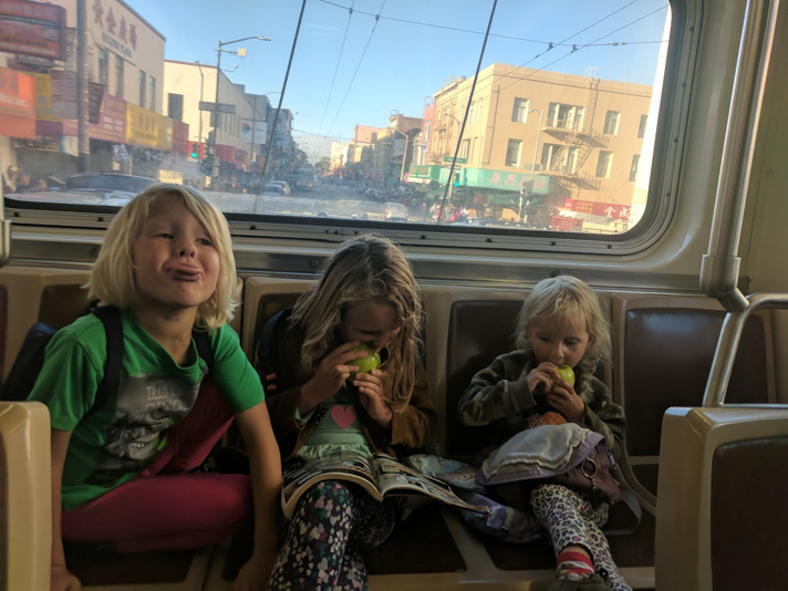 Three kids hanging out in the back of an SFMUNI bus