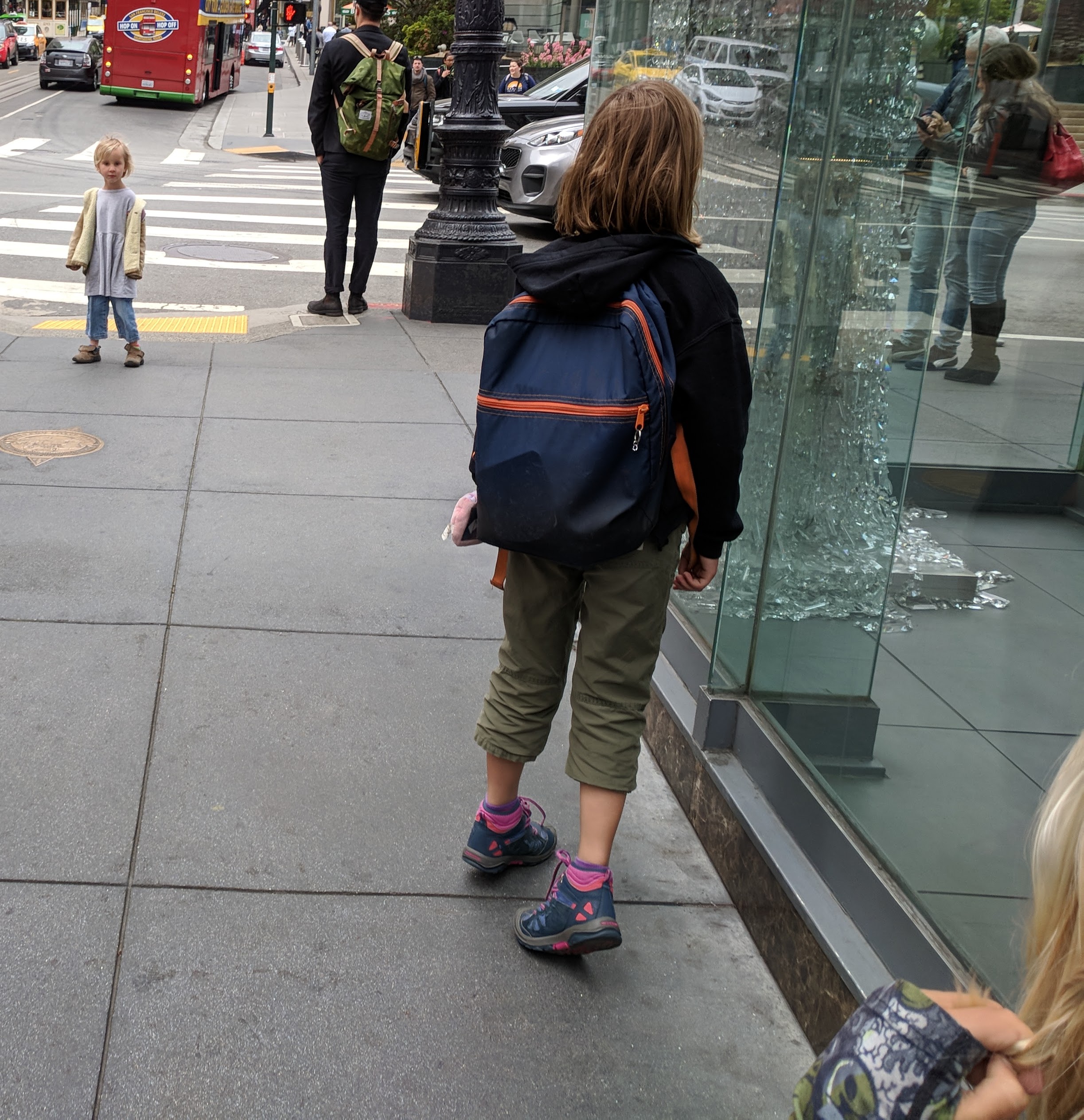 Three year old kid waiting at downtown intersection for her sibs to catch up